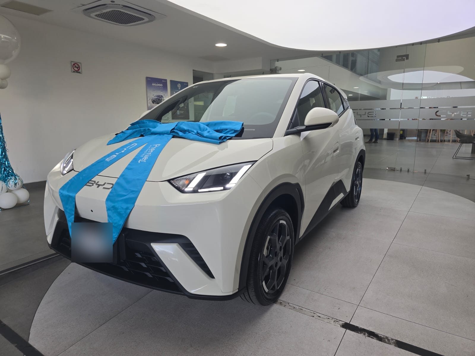 Vehículo eléctrico blanco con moño azul, vista de tres cuartos