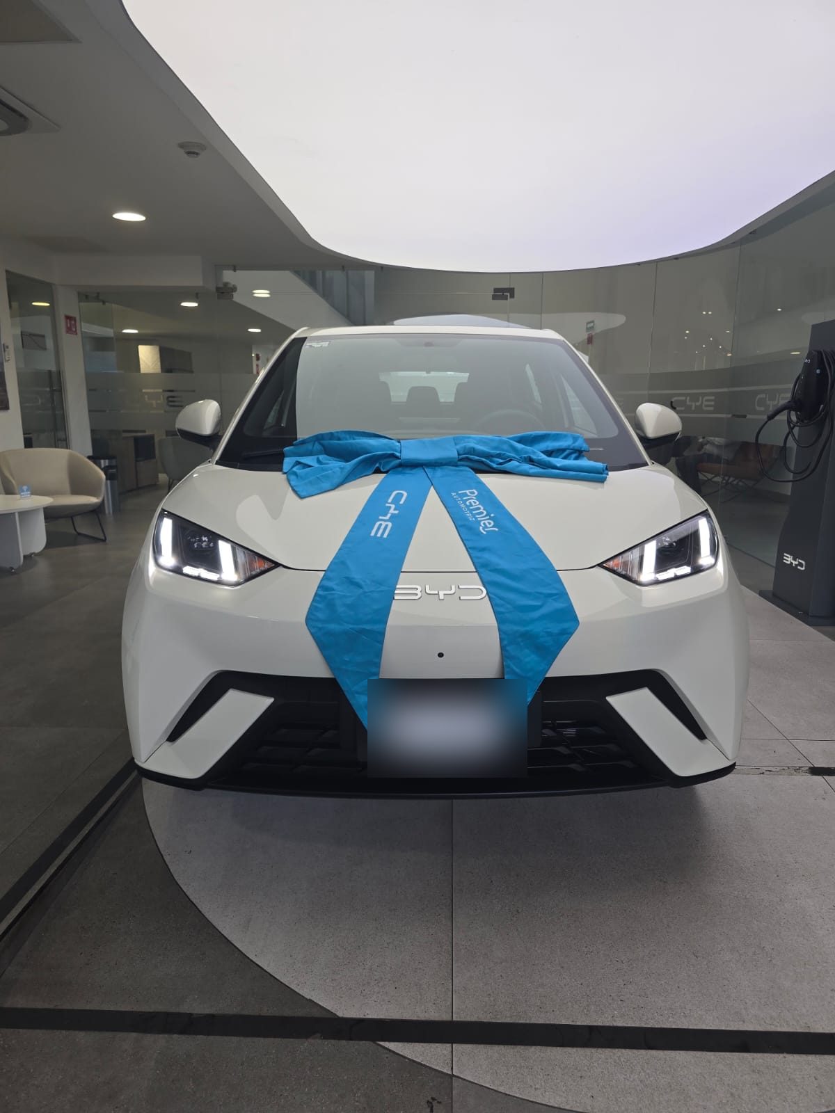 Vehículo eléctrico blanco con moño de entrega, vista frontal